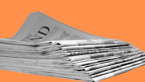 Stapel von Tageszeitungen vor orangem Hintergrund