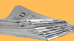 Stapel von Tageszeitungen vor gelbem Hintergrund